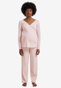 Light pink pajama set made of soft, ribbed fabric; features a wrap top with a V-neck and straight-leg pants with frayed edges.