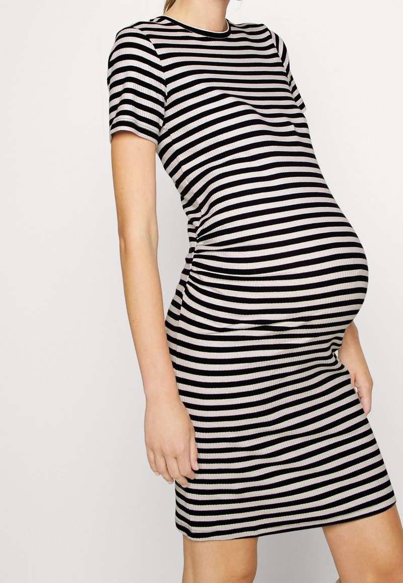 Robe de maternité rayée en noir et crème, manches courtes, silhouette ajustée, texture côtelée, longueur genou avec un col rond.