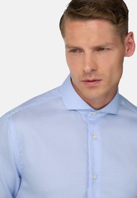Svetlo modrá kockovaná košeľa s golierom na gombíky a perlovo bielymi gombíkmi. Látka pôsobí hladko s jemnou textúrou a vzorom.