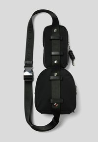 Borsa a tracolla nera in tessuto con tracolla regolabile, chiusura con zip e hardware in tonalità argento. Presenta due scomparti con una finitura testurizzata.