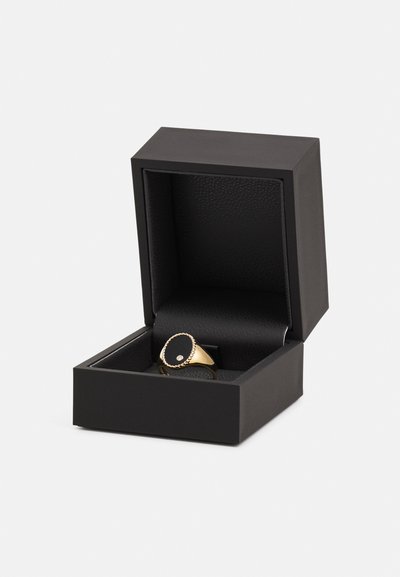 Gold ring featuring a black oval stone and textured band, presented in a black jewelry box with a smooth, leather-like interior.