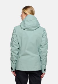 Giacca impermeabile verde menta chiaro con cappuccio, caratterizzata da un design aderente, polsini elasticizzati e un dettaglio con logo verde all'orlo.