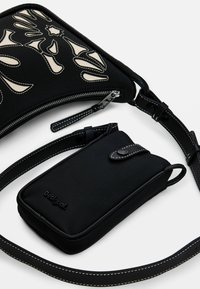 Borsa a spalla nera con motivi astratti a taglio crema, chiusura con zip e tracolla regolabile; include una pochette nera più piccola con chiusura a scatto.