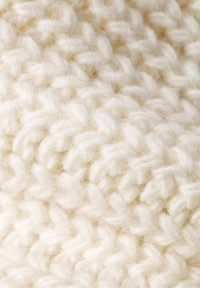 Gestrickter Stoff in Off-White, mit einer strukturierten Oberfläche, dicken, geschlungenen Maschen und einem weichen, flauschigen Aussehen.