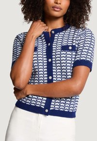 Granatowo-biały dziergany kardigan z krótkimi rękawami, z teksturowanym wzorem, klasycznym dekoltem oraz ozdobnymi okrągłymi guzikami.