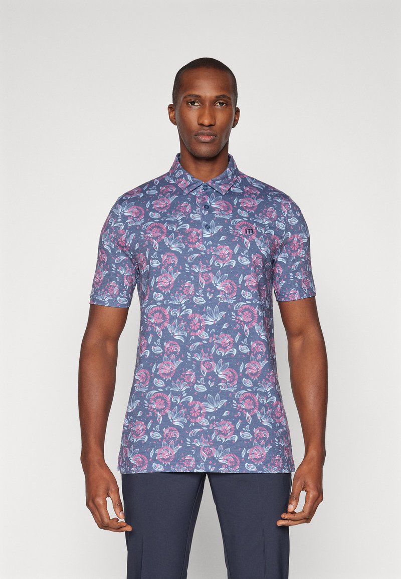 Polo a maniche corte di colore blu navy con un motivo floreale in rosa e blu. Presenta un colletto e una placca con tre bottoni. Realizzato in tessuto testurizzato.