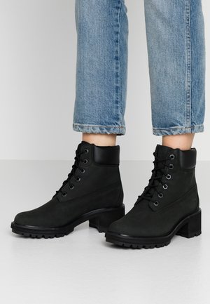 Black suede ankle boots with a textured upper, a smooth black leather collar, and a chunky heel. Features laces and a rugged sole.