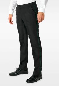 Schwarze Hose mit schmaler Passform, ausgestattet mit einem grünen Seitenstreifen. Hergestellt aus glattem Stoff, kombiniert mit glänzenden schwarzen Abend Schuhen.