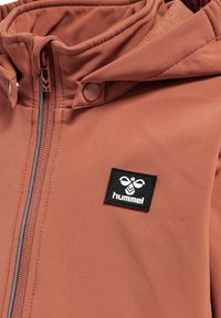 Braune Kapuzenjacke mit einem Frontreißverschluss, weicher Innenauskleidung und einem schwarzen Logopatch. Der Stoff ist glatt mit matter Oberfläche.