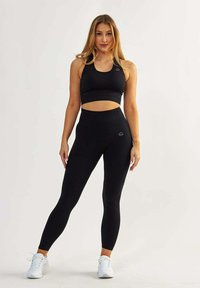 Black athletic crop top and high-waisted leggings, featuring textured fabric, a fitted design, and minimalistic brand logo accents.