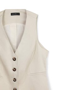 Beige ärmellose Weste mit tiefem V-Ausschnitt, vier dunklen Knöpfen vorne und einer kleinen Schlitztasche auf der rechten Seite.