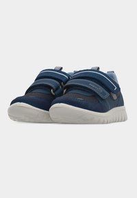 Ζευγάρι παιδικά αθλητικά παπούτσια σε ναυτικό μπλε με γκρι σόλες και διπλούς ιμάντες βέλκρο, που φαίνονται από μπροστά πάνω σε λευκό φόντο.