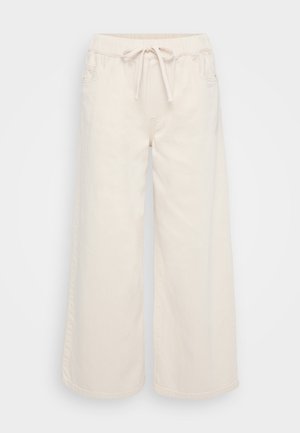 Calças largas de algodão, cor creme, com cintura elástica, cordão e bolsos laterais. Textura suave, design casual.