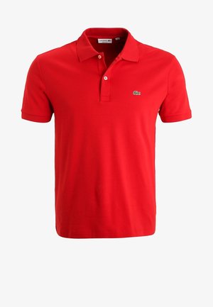 Polo rouge à manches courtes avec patte à deux boutons et petit logo crocodile vert sur la poitrine gauche.