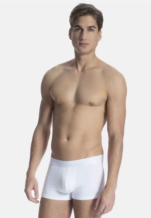 Valkoiset puuvillaiset boxerkalsarit, joissa on sileä pinta, tiukka istuvuus ja hillitty etusauma. Malli seisoo neutraalin taustan edessä.