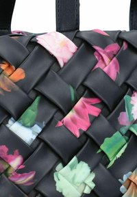 Borsa intrecciata in pelle nera con dettagli floreali in rosa, bianco e arancione. Presenta una superficie texture e un design intricato.