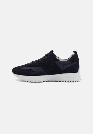 Zapatillas deportivas azul marino de ante con un upper texturizado, que cuentan con una suela de goma blanca y dentada y un diseño de puntera redonda.