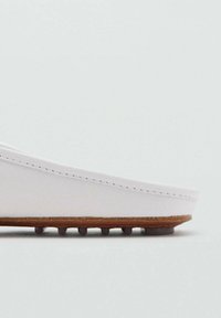 Scarpa bianca slip-on con tomaia in pelle liscia, dettagli cuciti e suola in gomma marrone a contrasto con piccoli ganci per la trazione.