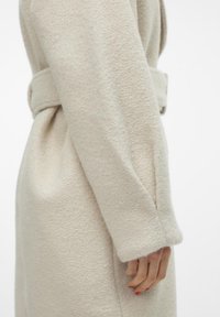Beige wollen jas met een zachte textuur, voorzien van een ceintuur in de taille, lange mouwen en een minimalistisch ontwerp. Geschikt voor een getailleerde look.