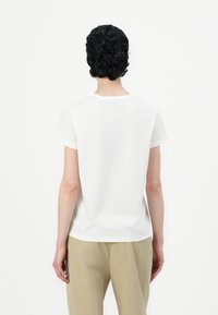 Weißes Baumwoll-T-Shirt mit klassischem Rundhalsausschnitt und kurzen Ärmeln, von hinten gezeigt. Es hat einen geraden Schnitt und eine weiche Textur.
