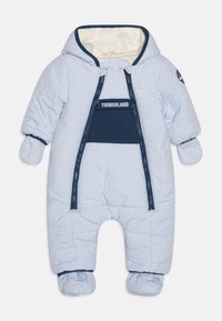 Combinaison de neige rembourrée bleu clair avec une capuche doublée en polaire, fermeture éclair à l'avant et poignets élastiques. Présente un panneau d'accent bleu marine et des manches couvertes de mitaines.