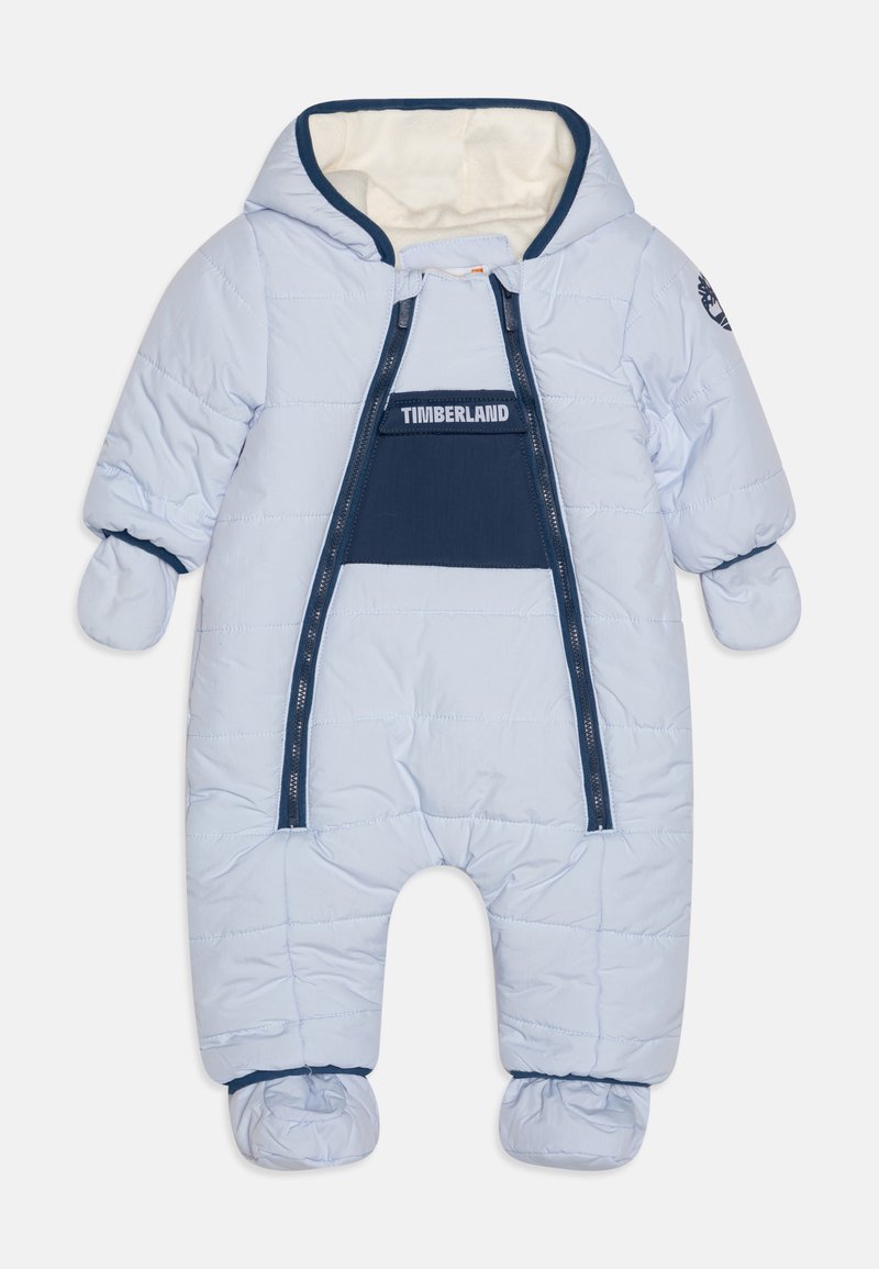 Combinaison de neige rembourrée bleu clair avec une capuche doublée en polaire, fermeture éclair à l'avant et poignets élastiques. Présente un panneau d'accent bleu marine et des manches couvertes de mitaines.