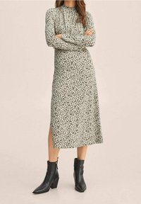 Groene bloemen midi-jurk met lange mouwen, bloemenpatroon, zijsplit, gecombineerd met zwarte enkelboots met een blokhak.