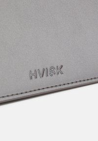Cartera de imitación cuero gris con el logo "HVISK" en relieve, detalles de costura fina y una textura suave. Diseño compacto, estilo minimalista.