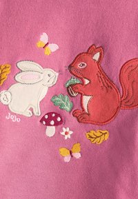 Bestickter Patch mit einem weißen Hasen und einem roten Eichhörnchen, umgeben von bunten Blättern, Pilzen und Schmetterlingen auf einem rosa Stoffhintergrund.