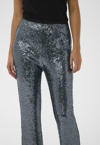 Silver sequin pants with a flared leg design, featuring a fitted waistband and shimmering texture that reflects light.
