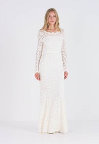 Pitkähihaista pitsistä valmistettua hääpukua off-white-värissä, istuva vartalon malli, liehuva alaosa, monimutkaisia kukkakuoseja ja sileä pinta.
