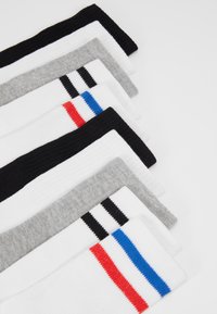 Set aus acht Socken in verschiedenen Farben: schwarz, weiß, grau. Jede Socke hat eine gerippte Textur und auffällige colored Streifen.