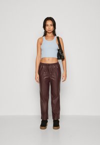 Lys blå ribbet crop top, burgunder faux skinnbukser med elastisk midjebånd, og svarte sneakers med teksturert såle. Svart veske.