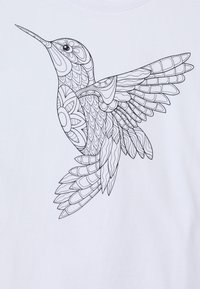 Bílý tričko se znakem podrobného černého obrysu kolibříka v letu, ukazujícího složité vzory na křídlech a těle.