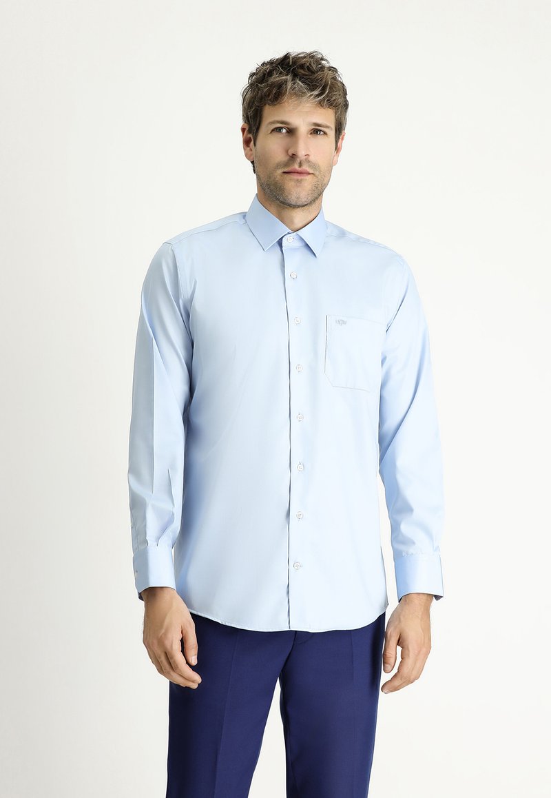 Camicia azzurra chiara a maniche lunghe con chiusura a bottoni e taschino sul petto. Vestibilità tailored, texture liscia e colletto appuntito. I bottoni sono bianchi.