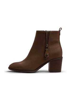 Bota marrón de ante hasta el tobillo con cremallera lateral y lengüeta para tirar, tacón de bloque apilado y punta redondeada, mostrada desde el lado interior sobre un fondo blanco.