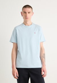 Tricou din bumbac de culoare bleu deschis, cu guler rotund, mâneci scurte și un mic logo roșu pe partea stângă a pieptului. Textură netedă.