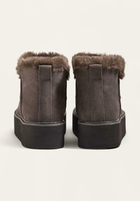 Barna velúrbokacsizma műszőrme béléssel és vastag fekete platform talppal, letisztult, minimalista dizájnnal és hátul húzófüllel.
