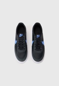 Baskets Nike noires avec des accents bleus, dotées d'une tige en cuir lisse, d'un bout rond, d'un design à lacets et d'une semelle extérieure en caoutchouc blanche.