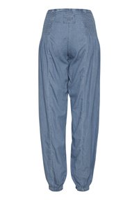 Pantalones jogger de denim azul claro con cintura y puños elásticos, mostrados desde la parte posterior, con parche de marca cosido en la cintura.