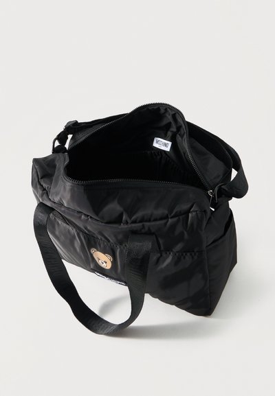 Μαύρη νάιλον τσάντα ώμου με ανοιχτό φερμουάρ, σχέδιο αρκουδάκι στο μπροστινό μέρος, μαύρες λαβές και εσωτερική ετικέτα που γράφει "Moschino".