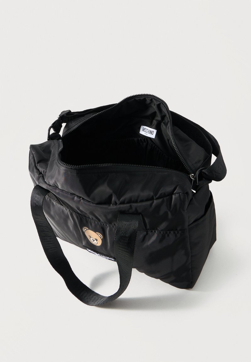 Black nylon shoulder bag with open zipper, teddy bear patch on front, black handles, and inner label reading "Moschino."