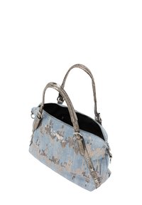 Denim håndtaske med sølv hardware, der har en lynlås lukning, en struktureret overflade og et mønster af perler i beige og sølvtoner.