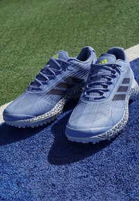 Blue athletic shoes with textured upper, black stripes, and a leopard-patterned outsole. Features a rounded toe and six eyelets for laces.