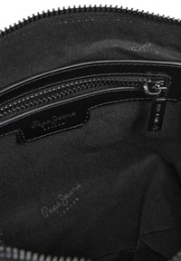 Schwarze Stofftasche mit Reißverschluss, innen glatt, mit einem Markenetikett und einer zusätzlichen Reißverschlusstasche mit silbernem Hardware.