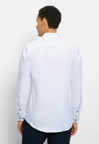 Weißes Langarmhemd mit spitzem Kragen, Manschetten mit dunkelblauen Knöpfen, glatter Textur und taillierter Silhouette.