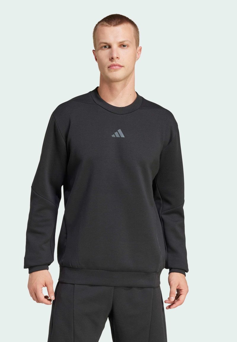 Black sweatshirt made of soft material, featuring a crew neckline, long sleeves, and a small gray logo on the chest. Fitted design.