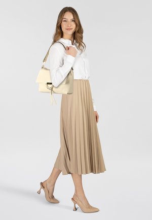 Borsa color crema con chiusura a patta e dettagli in oro, abbinata a una camicia bianca con bottoni e a una gonna beige a pieghe, indossata con scarpe con tacco color nude.