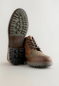 Brown leather and tweed shoes with a textured rubber sole. Features perforated detailing, lace closure, and a sturdy tread pattern.