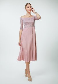 Off-the-shoulder dress in light pink featuring a lace bodice and pleated skirt, crafted from soft fabric with a flowing silhouette.